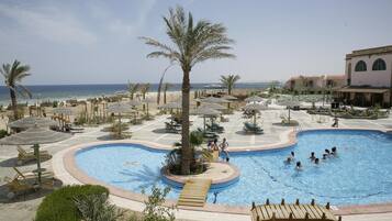 A resort pool area with multiple pools, lounge chairs, and umbrellas.