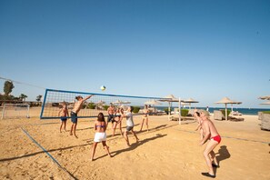 Un partido de voleibol de playa en desarrollo, con jugadores en trajes de baño.