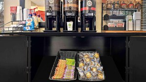 Ein Kaffeeangebot mit zwei Kaffeeautomaten, beschriftet als 'Dark Roast' und 'Light Roast', einem Kaffeeausgabegerät und einer Auswahl an verpackten Snacks.
