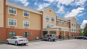 A multi-story hotel with a beige and brown facade, a parking lot, and a lobby entrance. - Extended Stay America - Fort Wayne - South (Fort Wayne)