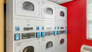 A laundry facility with multiple washing machines, each with a control panel and a label indicating the machine number. - Extended Stay America - Fort Wayne - South (Fort Wayne)