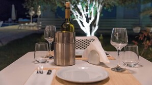 Mesa preparada para comer con una botella de vino, copas y cubiertos.