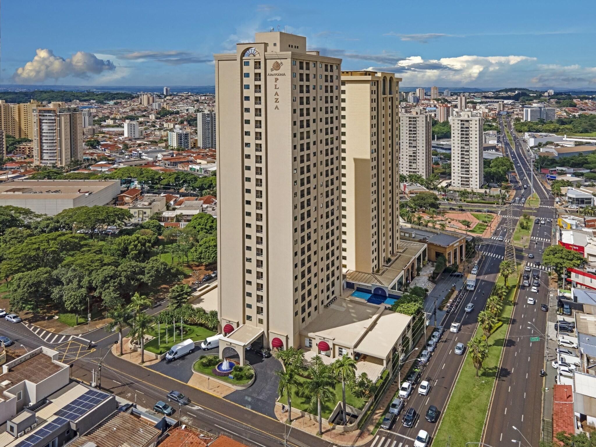 A high-rise building with a central entrance, surrounded by roads and other buildings.
