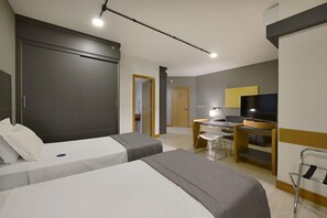 Una habitación de hotel con dos camas, un escritorio, una silla, un televisor y un armario.