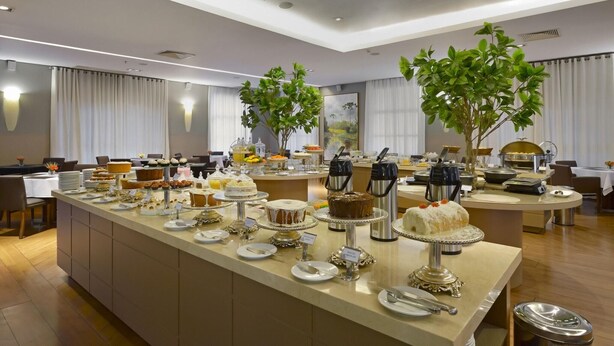 A hotel dining area with a buffet setup, including various food items and a coffee station. - Araucária Plaza (Ribeirão Preto)