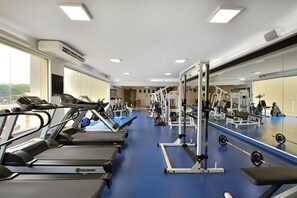 Ein Fitnessstudio mit Laufbändern, Kraftgeräten und einer Spiegelwand.