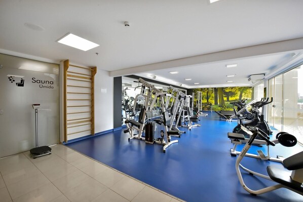 Une salle de sport équipée de matériel d’exercice, d’un sauna et dotée d’un sol bleu.