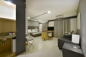 Habitación de hotel moderna con cama, escritorio, silla y una pequeña kitchenette.