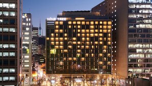 A modern hotel with a grid of windows, a prominent sign reading 'NINE TREE,' and a view of the surrounding urban area. - Nine Tree Premier Hotel Myeongdong2 (Seoul)