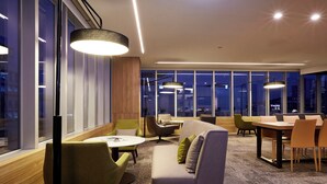 Ein modernes Interieur mit einer Couch, Sesseln, einem Tisch und Pendelleuchten.