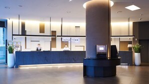 Ein modernes Hotel-Empfangsbereich mit einer Rezeption, einer großen Säule und einem Schreibtisch mit einem Bildschirm.