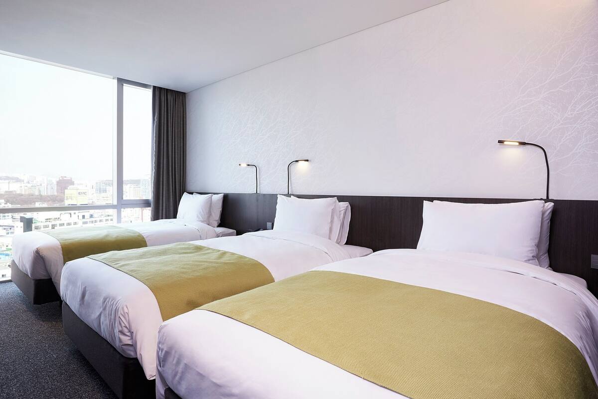 Et hotelværelse med to senge, et stort vindue og udsigt over byen.