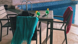 A poolside area with a table, chairs, and a towel. - Levatio Hotel (Muscat)