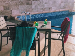 Zona de piscina amb taula, cadira i tovallola.