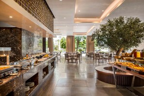 Un'area buffet con banconi in marmo, diversi tavoli da pranzo e un'ampia pianta al centro.