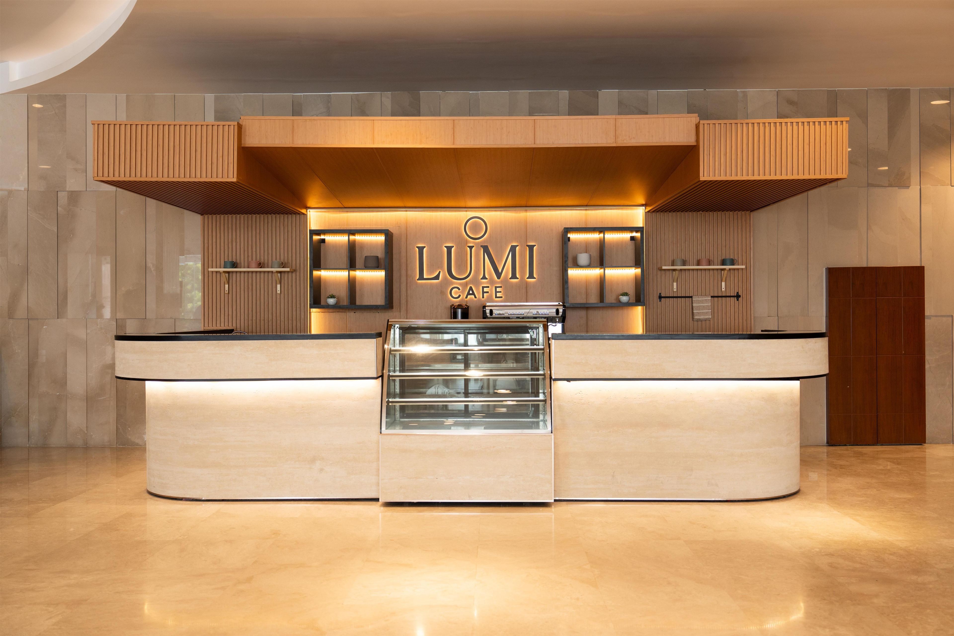 Un café LUMI moderno con una barra central, señalización iluminada y un diseño minimalista.