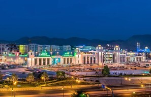 Panoramica urbana con un edificio importante, caratterizzato da un grande cartello, numerosi piani e una combinazione di strutture commerciali e residenziali.
