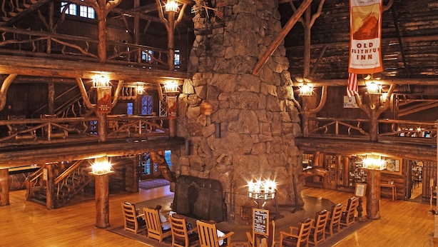 Un interior rústico con vigas de madera, paredes de piedra y una chimenea central.