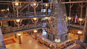 Un interior de madera con varios niveles, chimenea de piedra central, barandas de madera y zonas de estar.