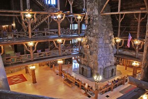 Un interior de madera con varios niveles, chimenea de piedra central, barandas de madera y zonas de estar.