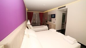 Una camera d'albergo con due letti, un bagno e vista sulla città.