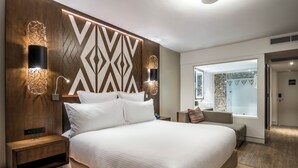 Een moderne hotelkamer met een groot bed, twee nachtkastjes, wandlampen en uitzicht op de badkamer.