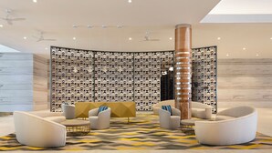 Een moderne lobby met een muur met een geometrisch patroon, een centrale kolom en moderne zitplaatsen.