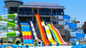 Ein Wasserpark mit mehreren Rutschen und einem Gebäude im Hintergrund, dessen Farbgestaltung blau und weiß ist.