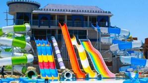 Um parque aquático com várias escorregas e um edifício de esquema de cores azul e branco ao fundo.