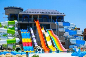 Parque acuático con varias toboganes y un edificio de fondo con decoración azul y blanca.
