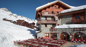 Un chalet de montagne doté d’un restaurant, d’une terrasse et entouré d’un paysage enneigé.