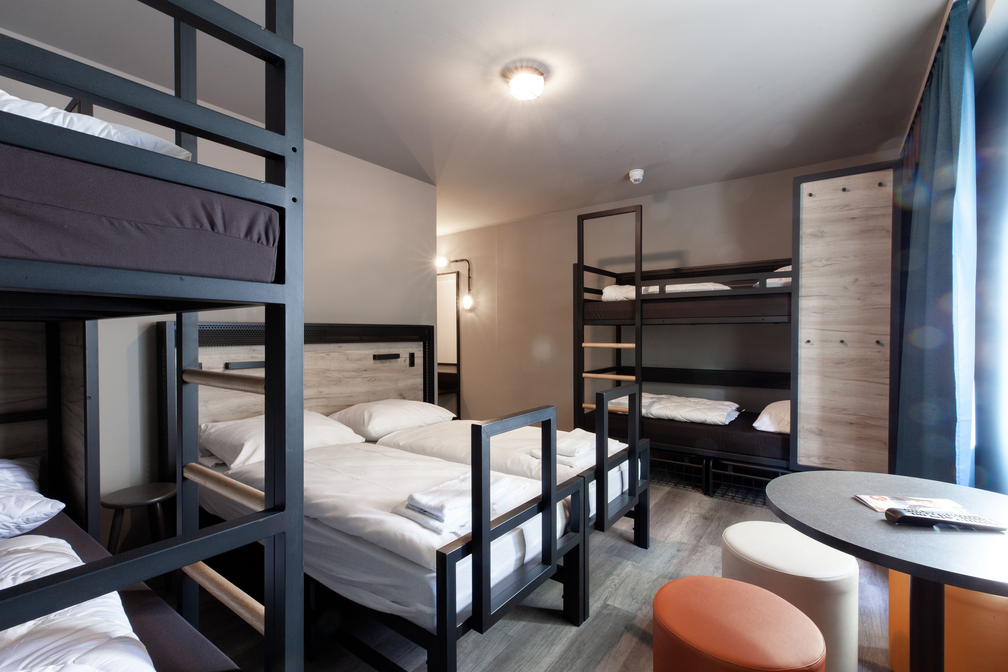 Ein Mehrbettzimmer mit einem runden Tisch und einem kleinen Hocker.