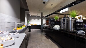 Um café moderno com um balcão extenso, máquinas de café e uma variedade de alimentos.