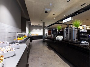 Un café moderno con una barra larga, máquinas de café y una variedad de alimentos.