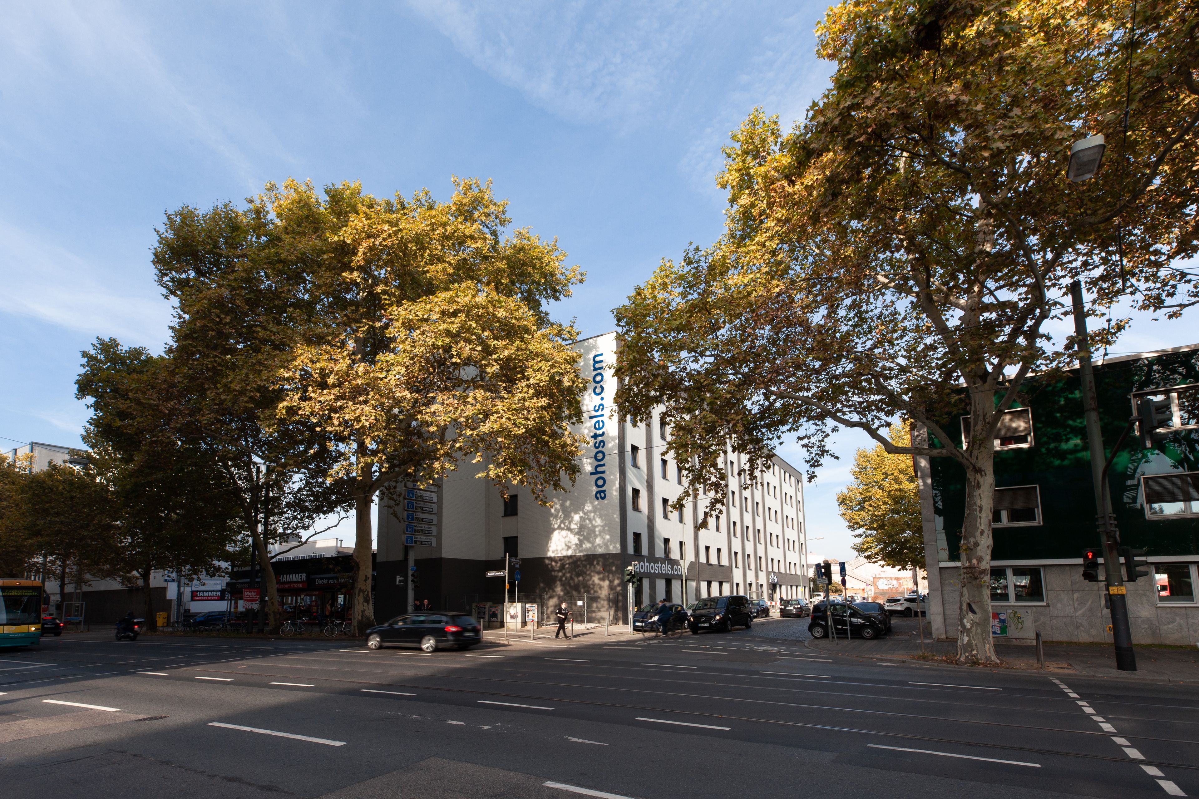 Straßenansicht mit einem Gebäude, auf dem 'aohotels.com' steht, und einem Bus im Vordergrund.