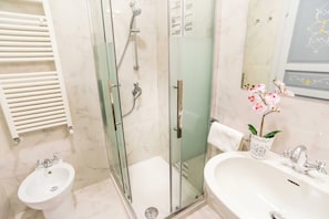 A bathroom with a glass-enclosed shower, a pedestal sink, and a vanity with a mirror. - CA VENICE (venezia)