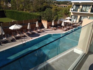 A pool with lounge chairs and umbrellas, surrounded by a wooden fence and greenery. - Selyria Resort (Zakynthos)