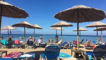 Une plage avec des chaises longues, des parasols et une terrasse en bois.