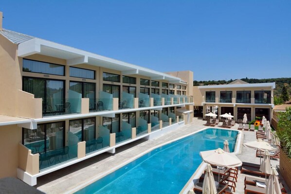 A hotel with a swimming pool, glass-enclosed balconies, and outdoor seating. - Selyria Resort (Zakynthos)