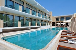 Un hotel con piscina, mobiliario exterior y un diseño arquitectónico moderno.