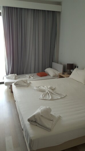 A hotel room with a large bed, two bedside tables, a nightstand, a lamp, and a window with curtains. - Selyria Resort (Zakynthos)