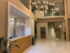 Eine großzügige Lobby mit einer Rezeption, einer Treppe und einer modernen Kronleuchter.