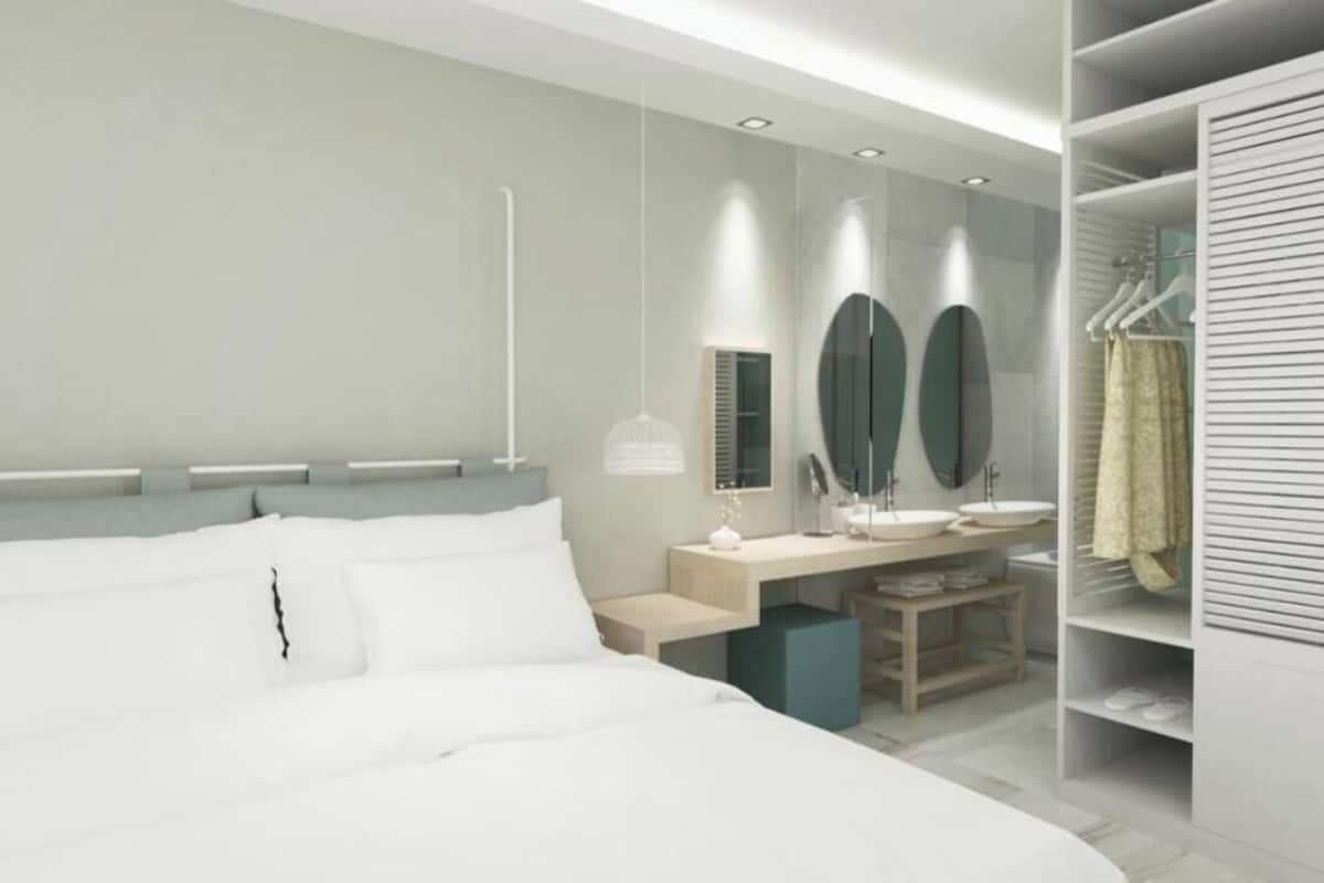Un dormitorio moderno con una cama grande, mesitas de noche, un escritorio y un vestidor con ropa colgada.