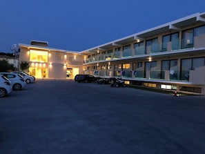 Ein modernes Hotel mit Parkplatz, mehreren Etagen und einem Balkon mit Glasgeländern.