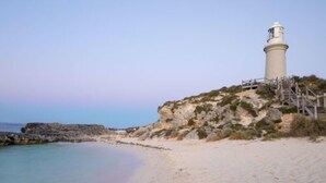 Un faro sobre un acantilado rocoso junto a una playa.