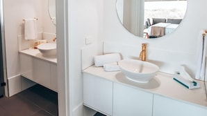 Ein modernes Badezimmer mit großem Spiegel, zwei Waschbecken und einer begehbaren Dusche.