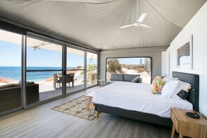 A bedroom with a bed, a desk, and a chair, with a view of the beach and ocean. - Discovery Holiday Parks - Rottnest Island (Perth)