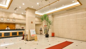 A hotel lobby with a reception desk, clocks, a red carpet, and a potted plant. - Shanghai Yuhang Hotel (Shanghai)