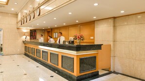 A hotel reception area with a marble counter, a clock, and a digital display. - Shanghai Yuhang Hotel (Shanghai)