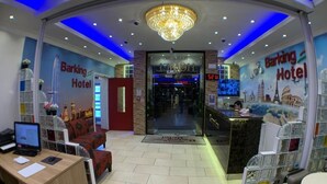 A hotel lobby with a reception desk, a chandelier, and a large sign for the Barking Hotel. - Barking Hotel  (Barking)